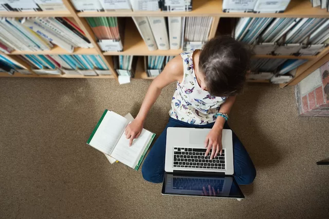 A high school student studies on a laptop in his bedroom