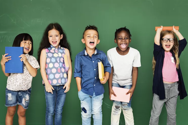 Smiling elementary students in front of a chalkboard