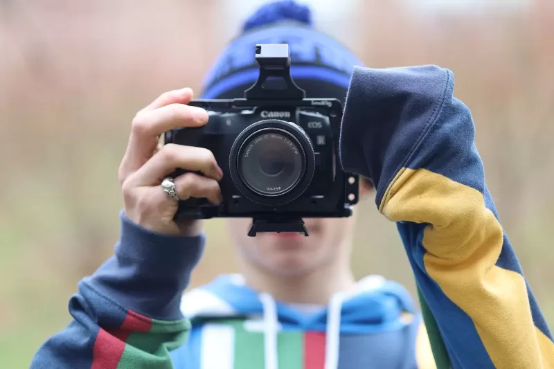 Photograph showing a student wielding a camera in front of their face, capturing a photograph.