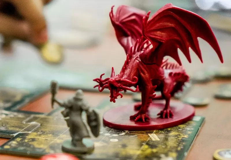 Photograph of two miniature figures, a dragon and a night, on a gameboard.