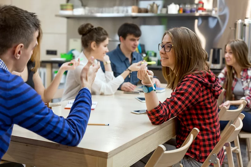 Photograph showing students gathered around a table having a friendly discussion