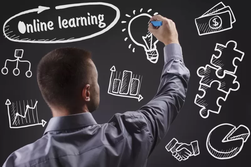 Image depicting a teacher writing on a chalkboard. The chalkboard features symbols of online learning such as charts and a lightbulk.