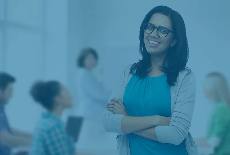 Image depicting a teacher posing in front of a classroom with other educators.