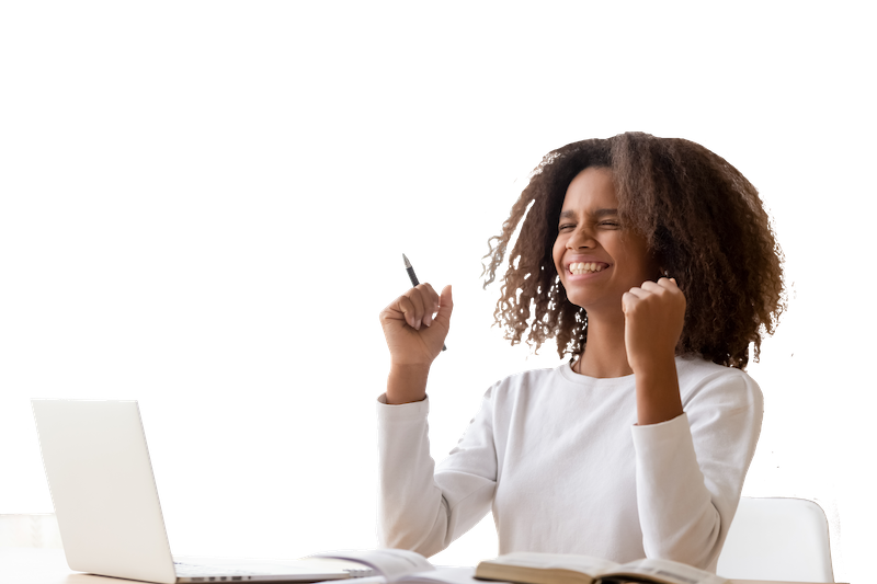 Student celebrates, eyes closed and smiling, with their fists aloft in front of a laptop while working at a deks.