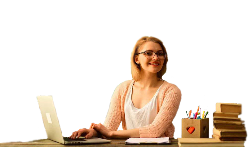 Photograph of a teacher at a desk working on a laptop with books, a pencil cup, and a clipboard beside them